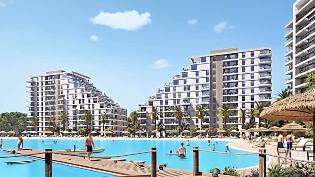Render de tres torres de Marena frente a la laguna cristalina, con palmeras y sombrillas en la playa de arena blanca.