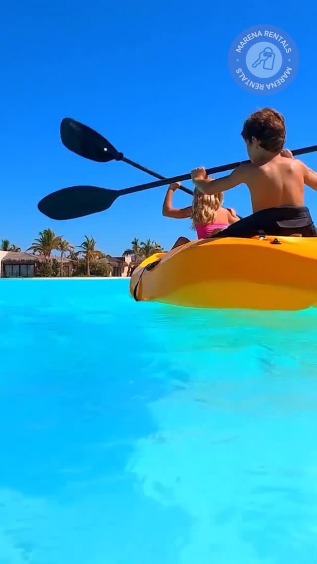 Dos niños remando en kayak sobre las aguas turquesas de la laguna cristalina.